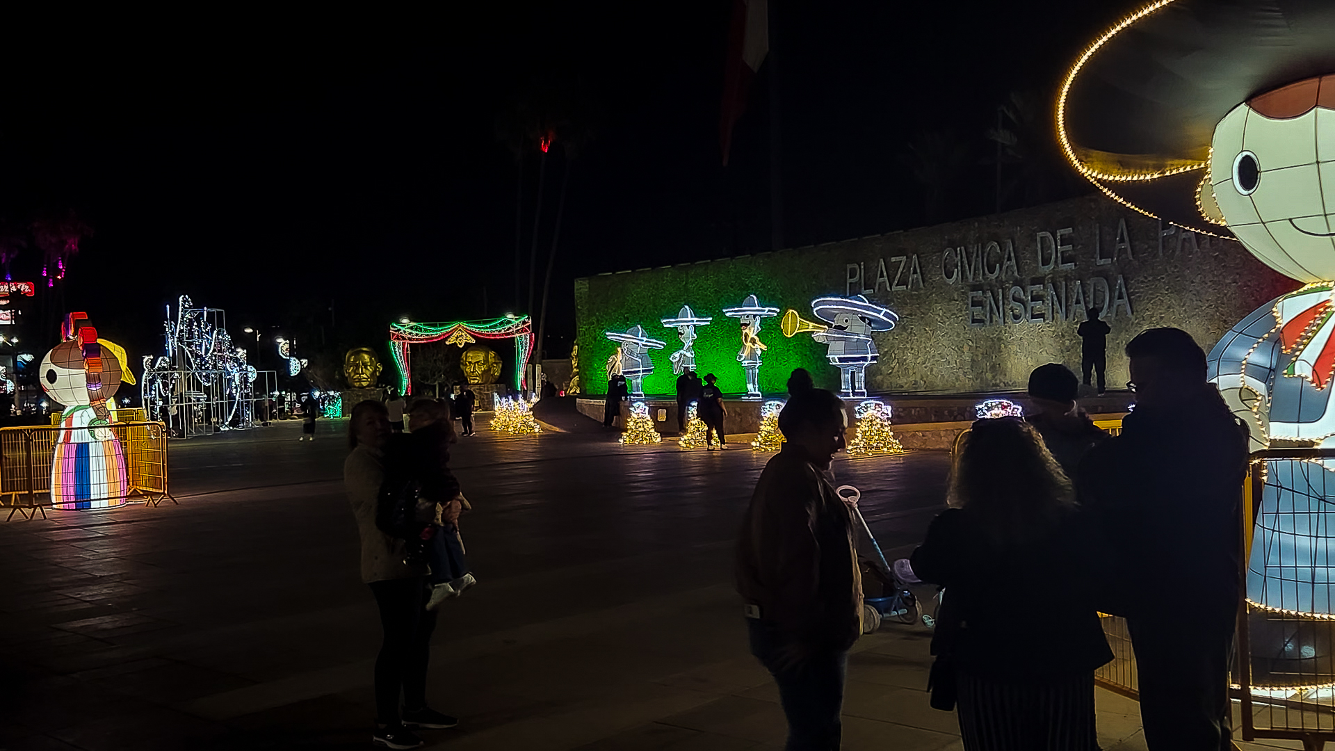 Personas disfrutando los Adornos de Temporada Patrios frente al monumento a la patria en Ensenada