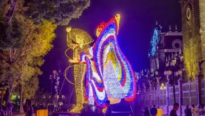 Vista lateral de las Figuras de luz Monumentales de charro y bailarina en el zócalo de Puebla durante las fiestas patrias. De fondo el lateral de la Catedral con iluminación dinámica generando photomoments